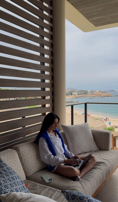 Woman working from a beachfront balcony sofa